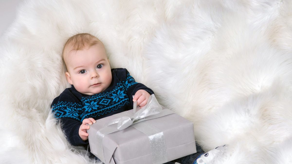 Baby i genser som holder en innpakket gave