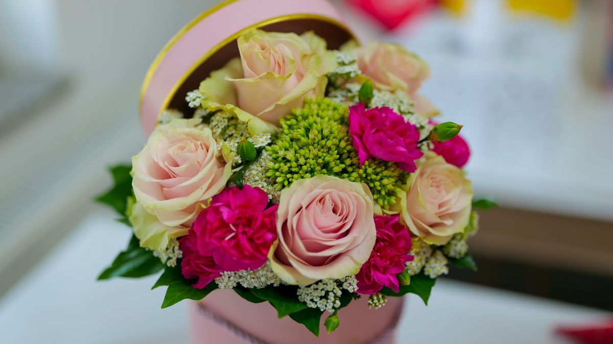 Rosa roser og nelliker i en rosa hatteeske