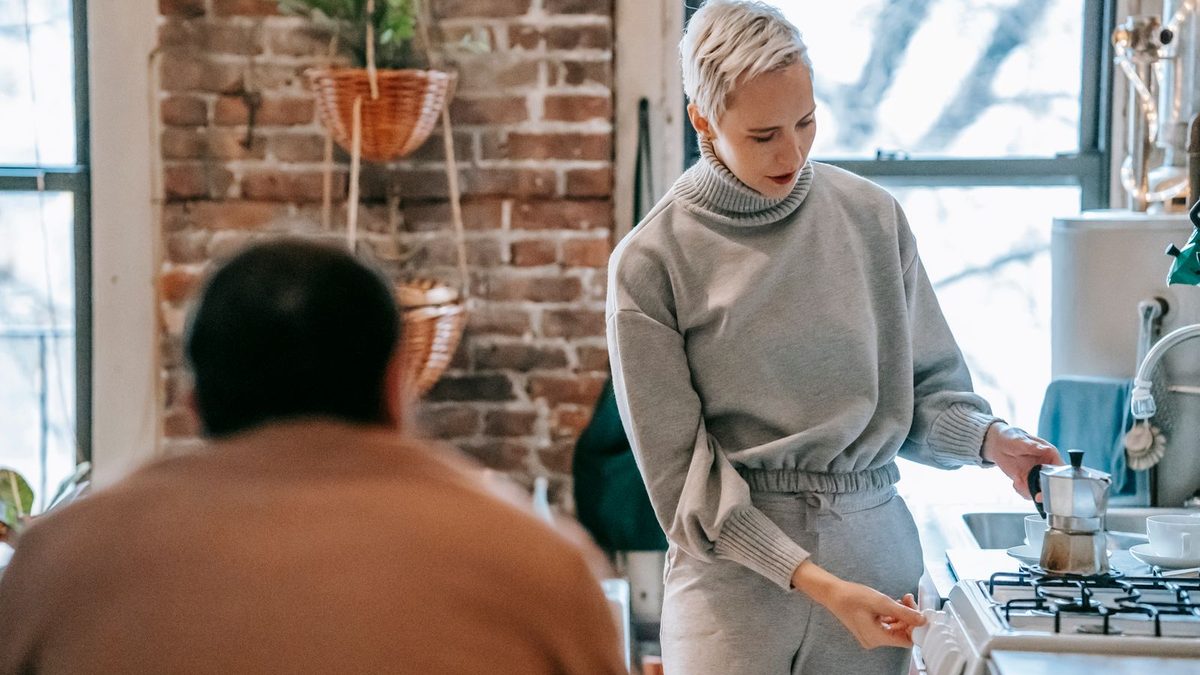 Kvinne som brygger kaffe i en espressokanne på komfyren
