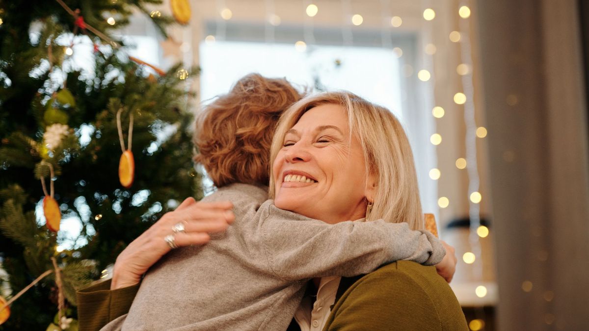 Kvinne som gir en varm klem ved juletreet
