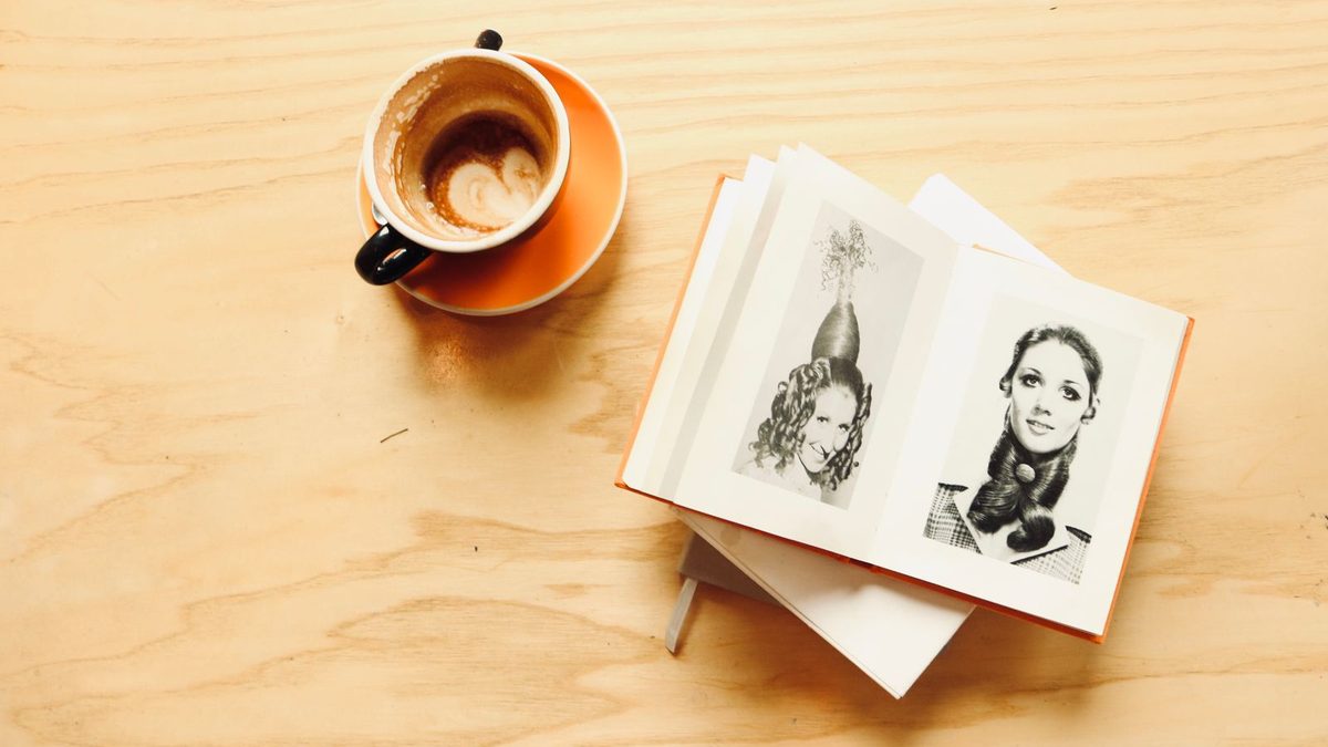 Åpen bok med tegninger ved siden av en kaffekopp