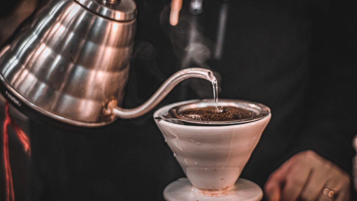 Kaffe som helles fra en kanne med svanehals over et filter